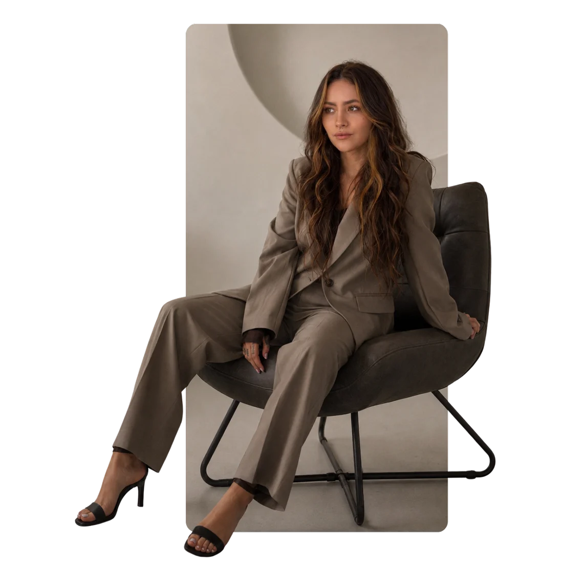 Amanda sentada numa poltrona, de terno taupe